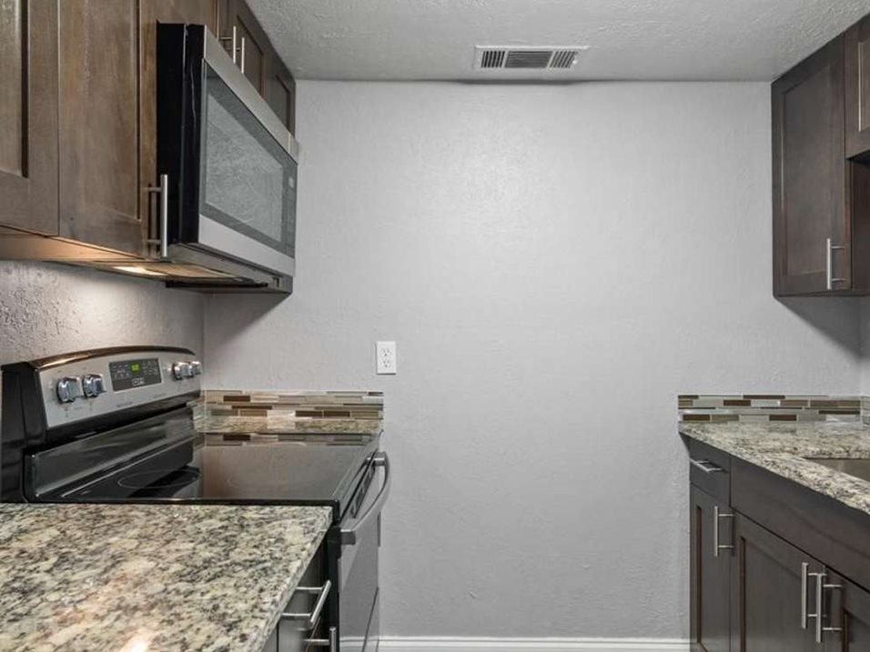 A kitchen with granite countertops and wooden cabinets.